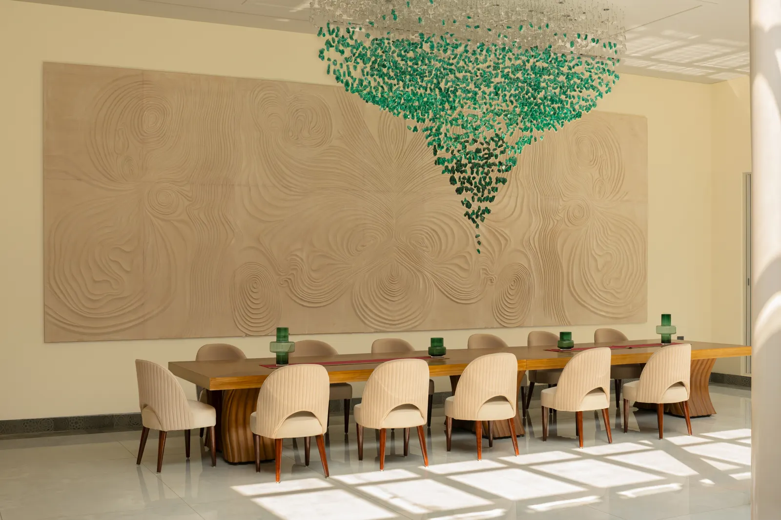 Villa Raag’s long dining table beneath the blue-green glass chandelier