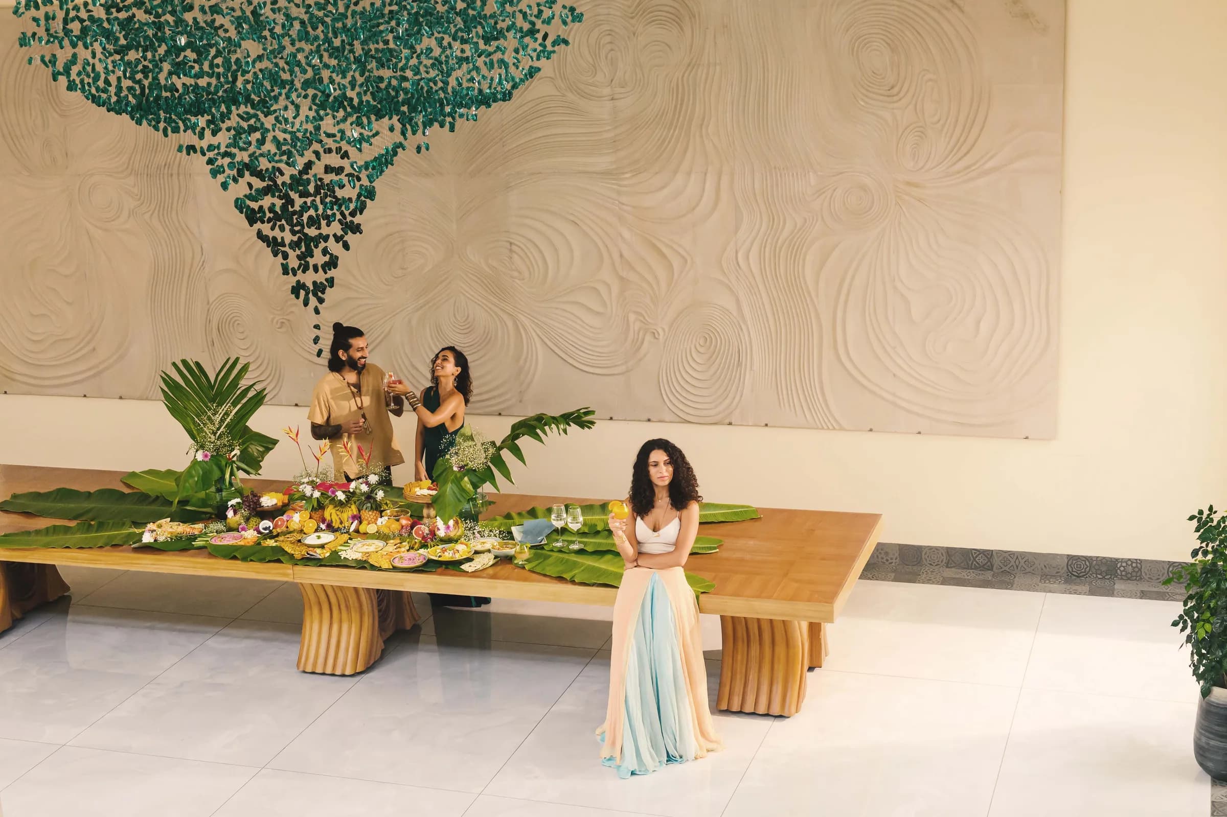 Une longue table à manger sous une installation suspendue verte
