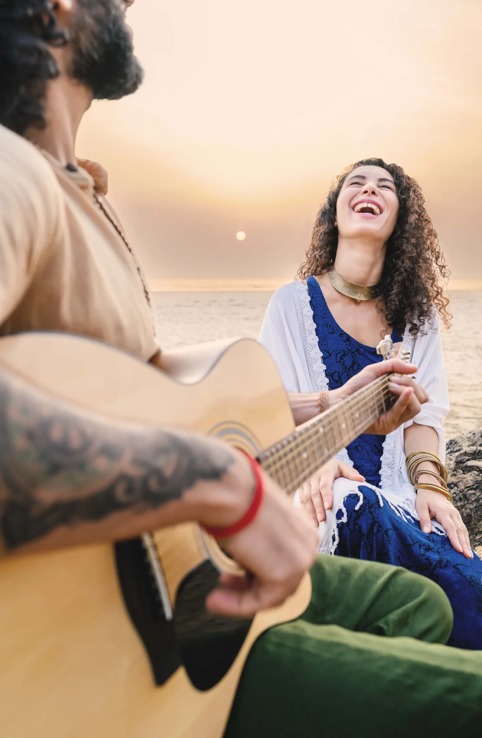 Zwei Menschen mit einer Gitarre am Meer