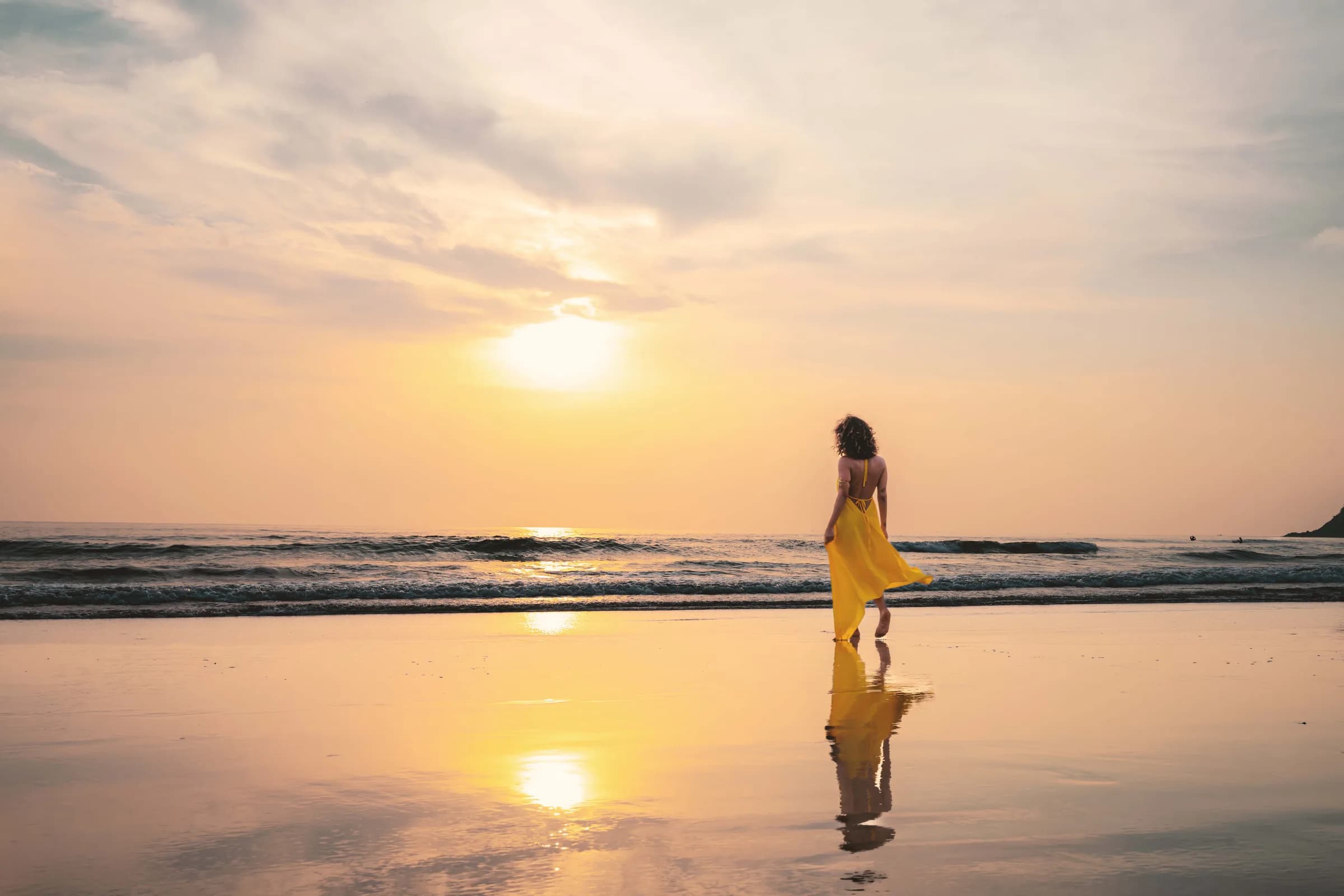 Una persona camina por la orilla al atardecer