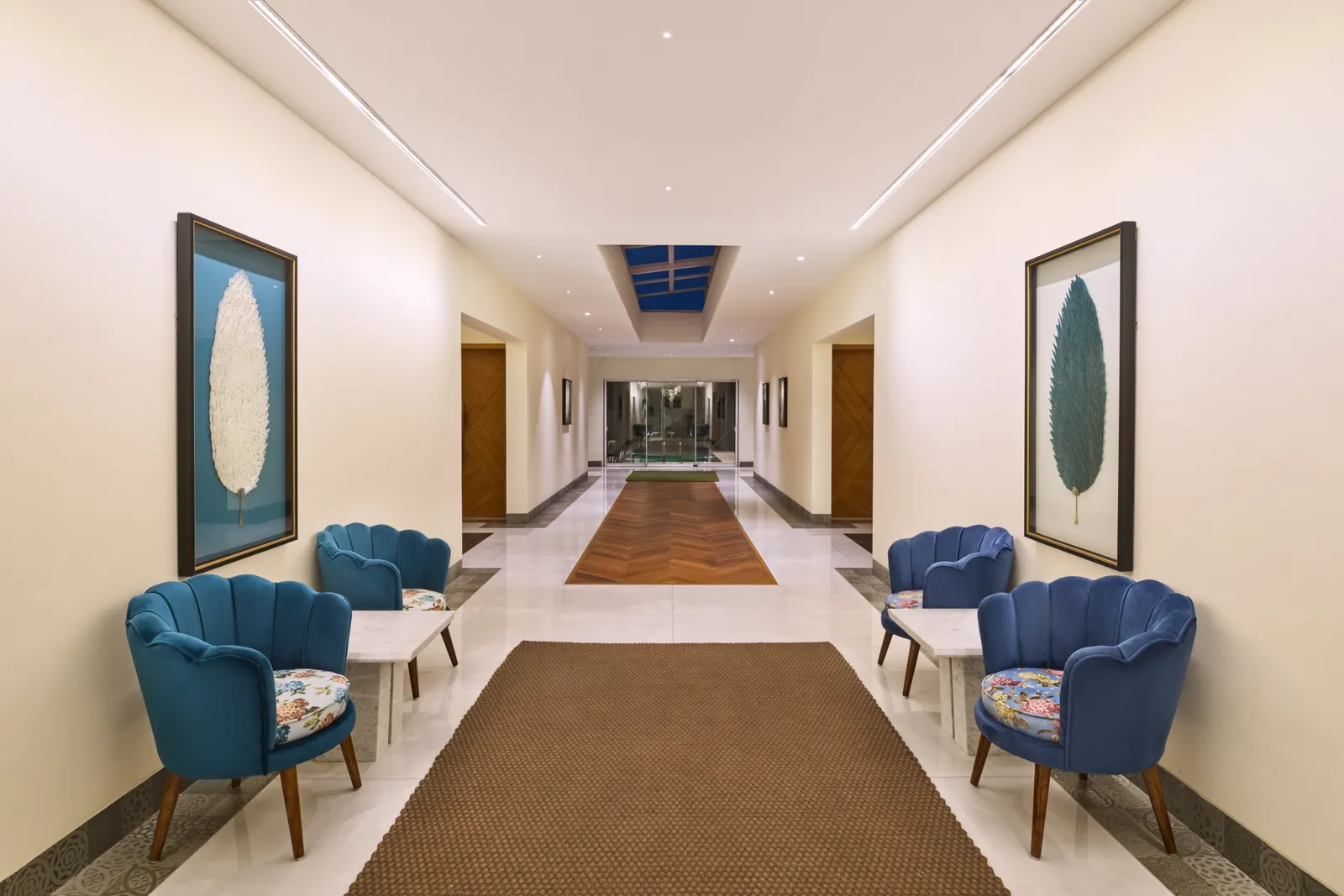 A seating-lined corridor with a skylight and feather artwork